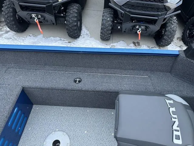 Slide: The Image of 2024 Lund 1650 Angler Sport interior with gray flooring, near off-road vehicles. - 12