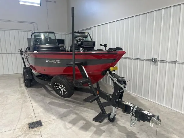 Slide: The Image of 2024 Lund 2025 Impact XS Sport boat in a garage, red exterior, on a trailer. - 20