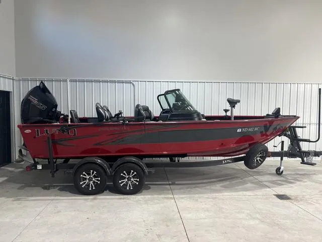 Slide: The Image of 2024 Lund 2025 Impact XS Sport boat, red and black, on a trailer in a garage. - 7