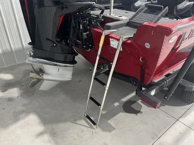 Slide: The Image of 2024 Lund 2025 Impact XS Sport boat with ladder and motor, in a garage setting. - 9