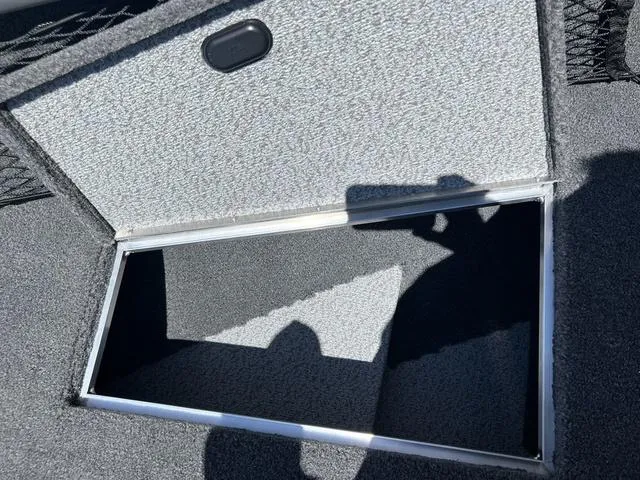 Slide: The Image of 2024 Lund 2025 Impact XS Sport boat storage compartment, open and empty, with carpeted interior. - 17