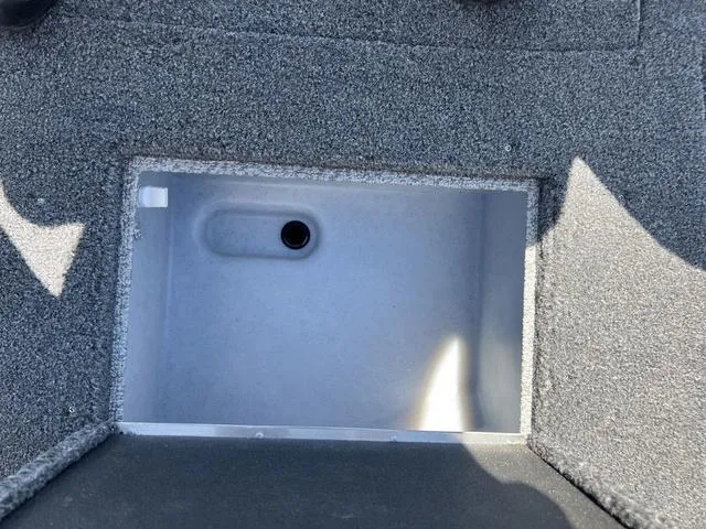 Slide: The Image of 2024 Lund 2025 Impact XS Sport boat storage compartment, gray interior, top view. - 19