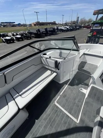 Slide: The Image of 2024 Yamaha Boats AR190 interior with seating and windshield, parked outdoors. - 19