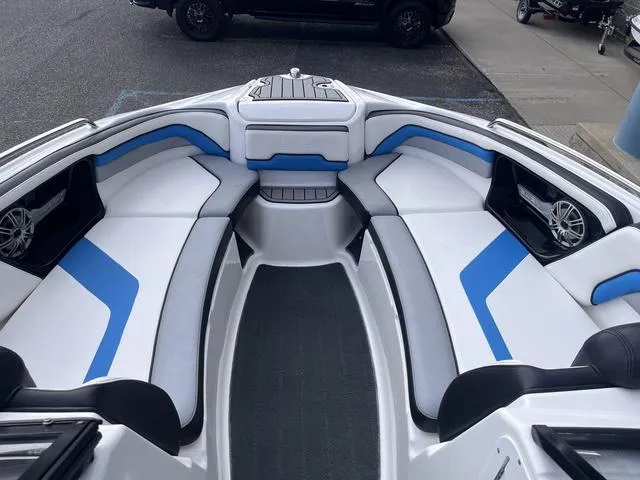 Slide: The Image of 2016 Yamaha Boats 242X E-Series interior with blue and white seating, docked outdoors. - 13