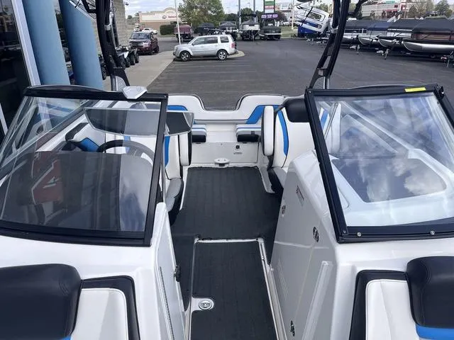 Slide: The Image of 2016 Yamaha Boats 242X E-Series interior with seating and windshield, parked in a dealership lot. - 18