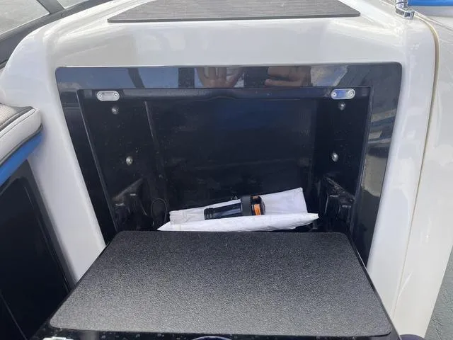 Slide: The Image of Open storage compartment on a 2016 Yamaha Boats 242X E-Series, containing a flashlight. - 22