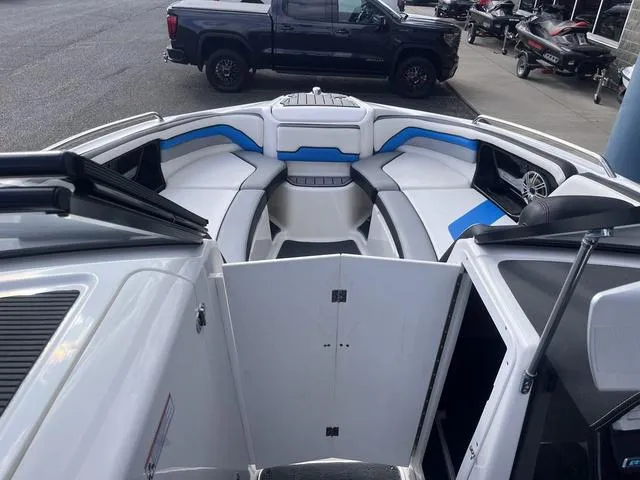 Slide: The Image of 2016 Yamaha Boats 242X E-Series interior with white and blue seating, parked near a black truck. - 25