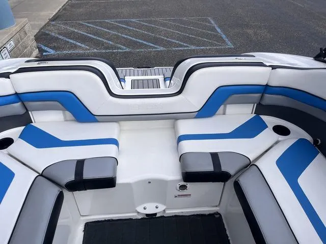 Slide: The Image of 2016 Yamaha Boats 242X E-Series interior with blue and white seating, docked on pavement. - 29