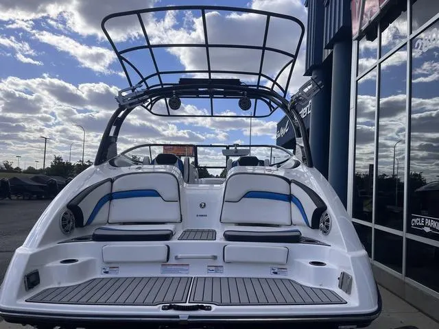 Slide: The Image of 2016 Yamaha Boats 242X E-Series, rear view, showcasing seating and wakeboard tower under cloudy sky. - 6