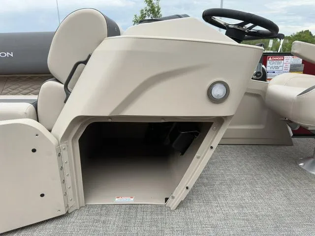 Slide: The Image of 2024 Bennington 22 SSR Tri-Toon Pontoon helm storage compartment, beige interior, steering wheel visible. - 29