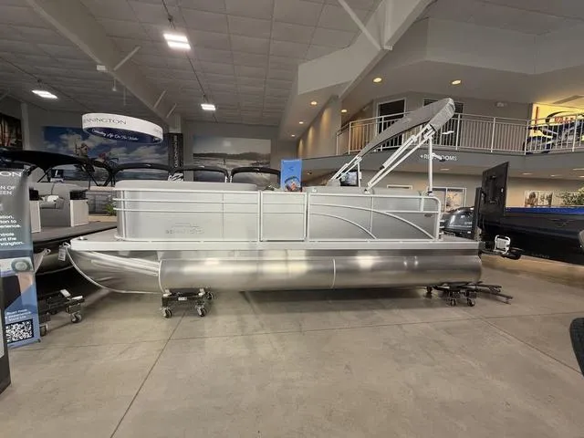 Slide: The Image of 2024 Bennington 208SLJ pontoon boat displayed in a showroom setting. - 1