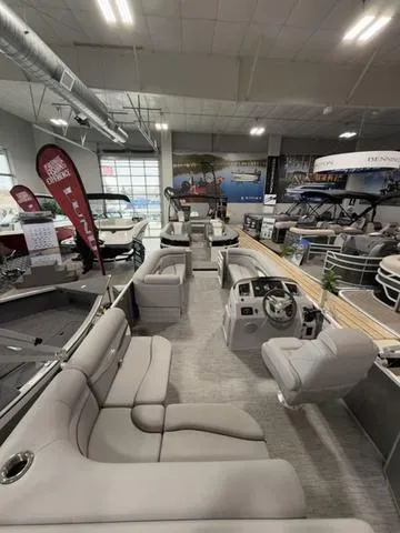 Slide: The Image of 2024 Bennington 208SLJ pontoon boat interior in showroom, featuring plush seating and modern helm. - 24