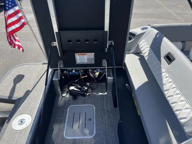 Slide: The Image of 2024 Bennington 25RX Swingback ESP Tri-Toon Pontoon interior with open storage compartment and American flag. - 25