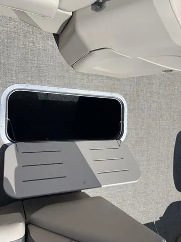 Slide: The Image of 2024 Bennington 22SSB-SPS boat interior with open storage compartment and beige seating. - 14