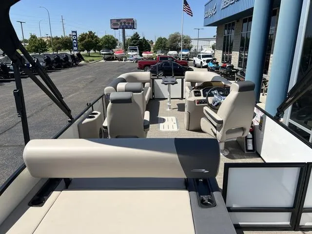 Slide: The Image of 2024 Bennington 22SSB-SPS pontoon boat interior with seating and helm, parked at dealership. - 24