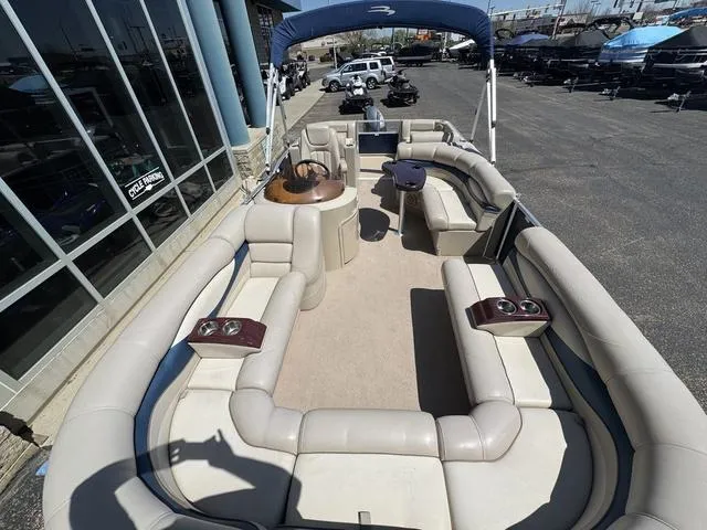 Slide: The Image of 2010 Bennington 2250RCW Pontoon with spacious seating and canopy, parked near a showroom. - 2