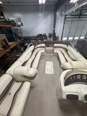 Slide: The Image of 2005 Bennington 2575RLX Pontoon boat interior with beige seating in a storage facility. - 12