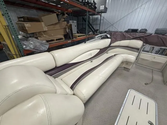 Slide: The Image of 2005 Bennington 2575RLX Pontoon boat interior with cream and brown seating in a storage area. - 13