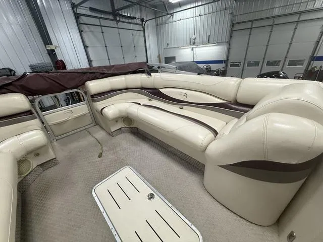 Slide: The Image of 2005 Bennington 2575RLX Pontoon interior with beige seating in a spacious garage. - 14