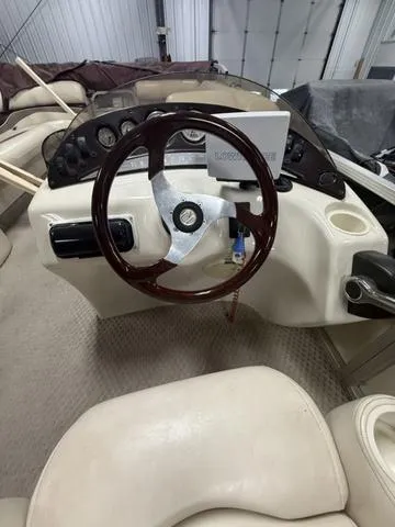 Slide: The Image of 2005 Bennington 2575RLX Pontoon boat steering console with wood-accented wheel and beige interior. - 8