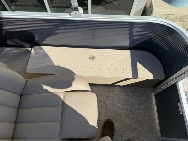 Slide: The Image of 2019 Bennington 21 SSX boat interior with beige seating and storage compartment. - 15