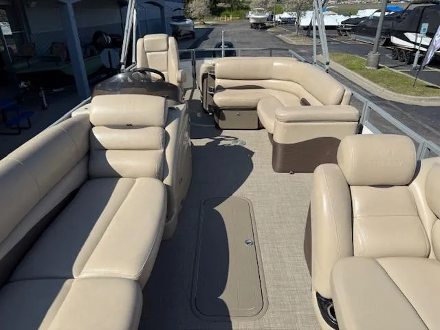 Slide: The Image of 2016 Regency 254 DL3 pontoon boat with spacious beige seating and helm, docked at marina. - 32
