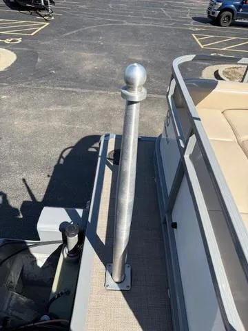 Slide: The Image of 2016 Regency 254 DL3 pontoon boat with beige seating and metal railing in a parking lot. - 5