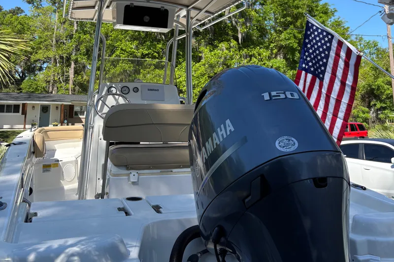 Slide: The Image of 2018 NauticStar 211 Hybrid boat with Yamaha engine and American flag in a residential setting. - 3
