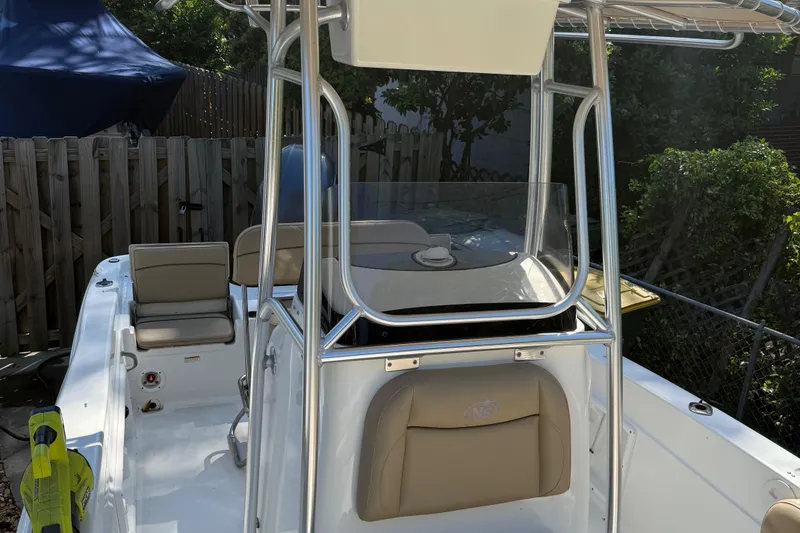 Slide: The Image of 2018 NauticStar 211 Hybrid boat with seating and console, docked outdoors. - 4