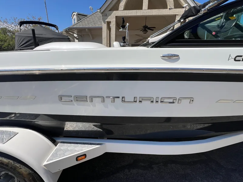 Slide: The Image of 2016 Centurion Carbon Pro boat side view with logo, parked near a house. - 8