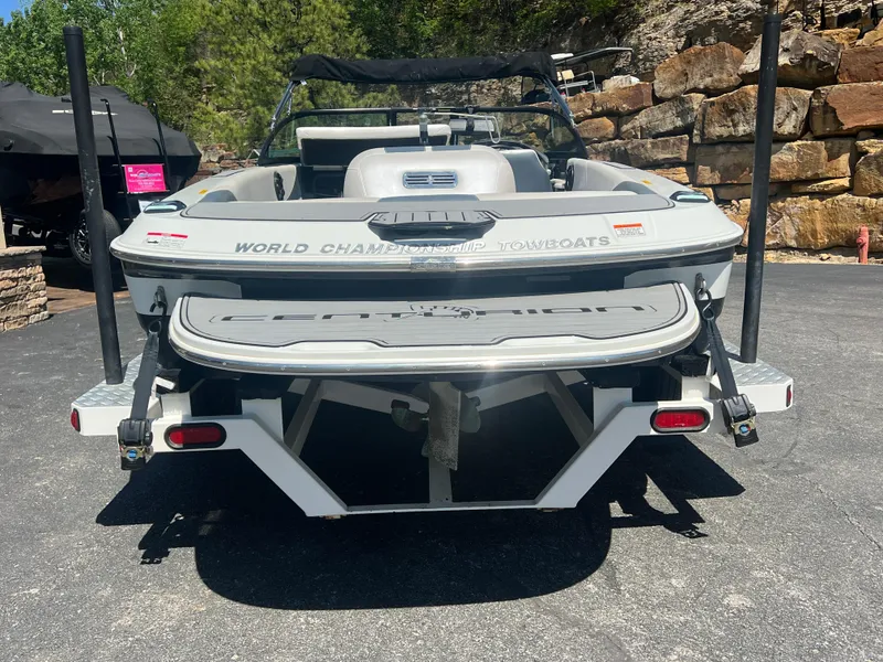 Slide: The Image of 2016 Centurion Carbon Pro boat, rear view, parked on pavement with rocky background. - 9