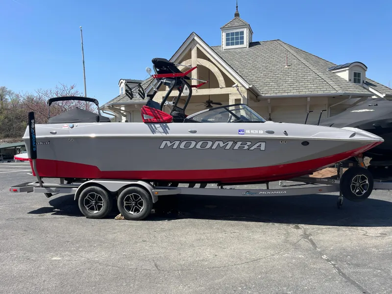 Slide: The Image of 2022 Moomba Makai boat on trailer, parked outside a building with a gabled roof. - 0