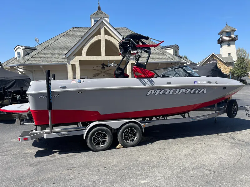 Slide: The Image of 2022 Moomba Makai boat on trailer, gray and red, parked near a house. - 1