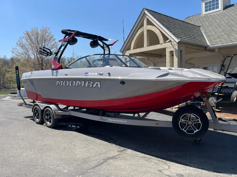 Slide: The Image of 2022 Moomba Makai boat on trailer, gray and red design, parked near a building. - 2