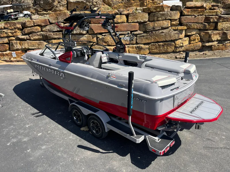 Slide: The Image of 2022 Moomba Makai boat on trailer, gray and red design, parked on asphalt near stone wall. - 5