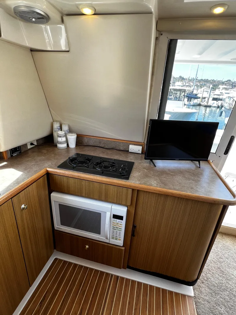 Slide: The Image of 2001 Bayliner 3488 Command Bridge Motoryacht kitchen with stove, microwave, and marina view. - 31