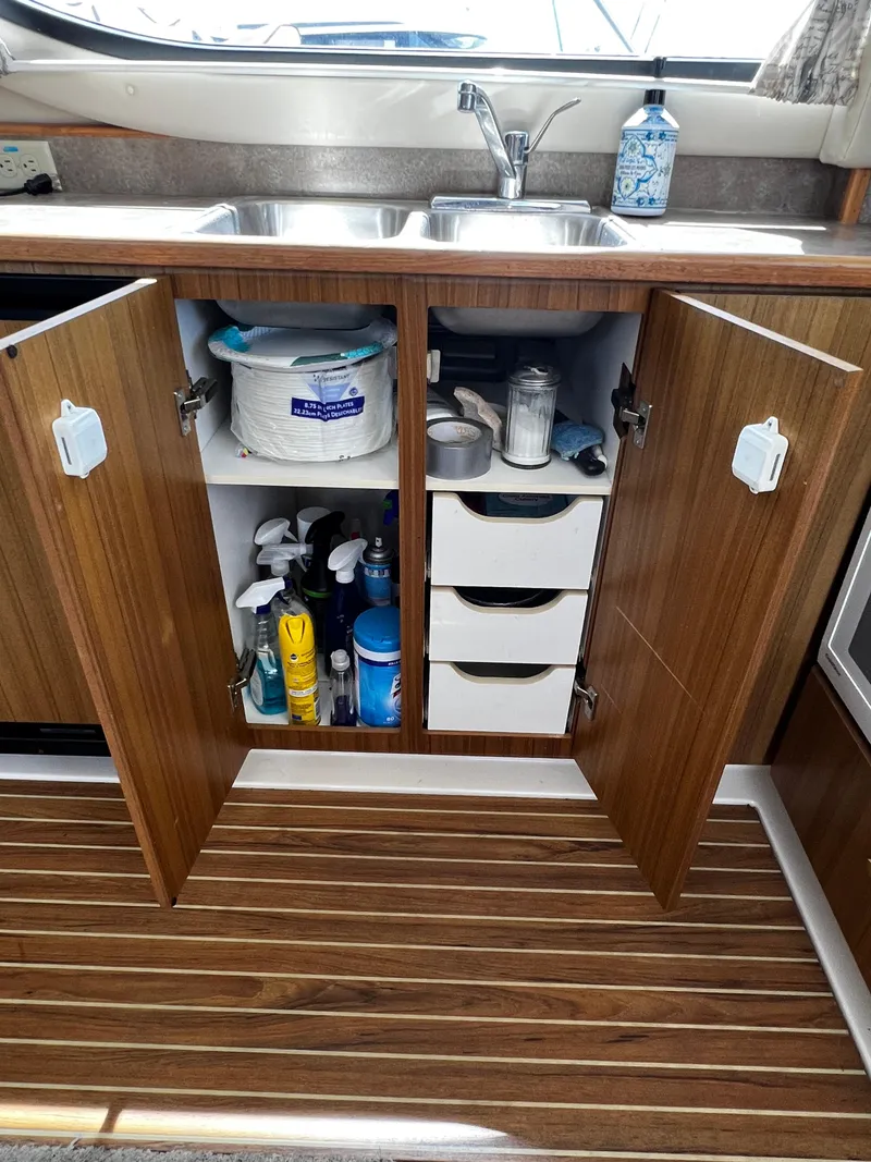 Slide: The Image of 2001 Bayliner 3488 Command Bridge Motoryacht kitchen with open cabinets and cleaning supplies. - 32