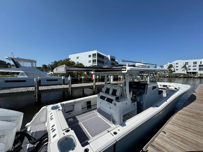 Slide: The Image of 2024 Tidewater 380 CC Adventure boat docked at marina under clear blue sky. - 14