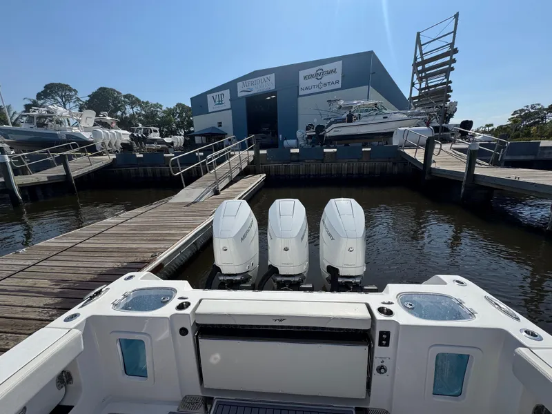 Slide: The Image of 2024 Tidewater 380 CC Adventure boat docked with triple engines at a marina. - 19