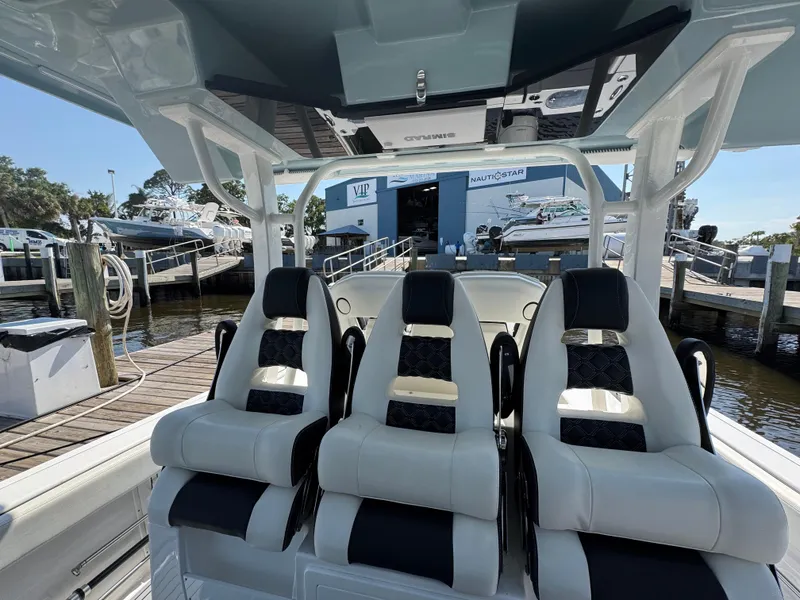 Slide: The Image of 2024 Tidewater 380 CC Adventure boat interior with three luxury seats at a marina. - 21