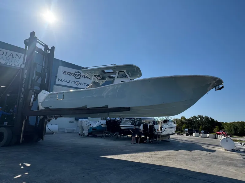 Slide: The Image of 2024 Tidewater 380 CC Adventure boat lifted by forklift under clear blue sky. - 3