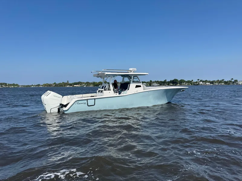 Slide: The Image of 2024 Tidewater 380 CC Adventure boat cruising on open water under clear blue skies. - 45