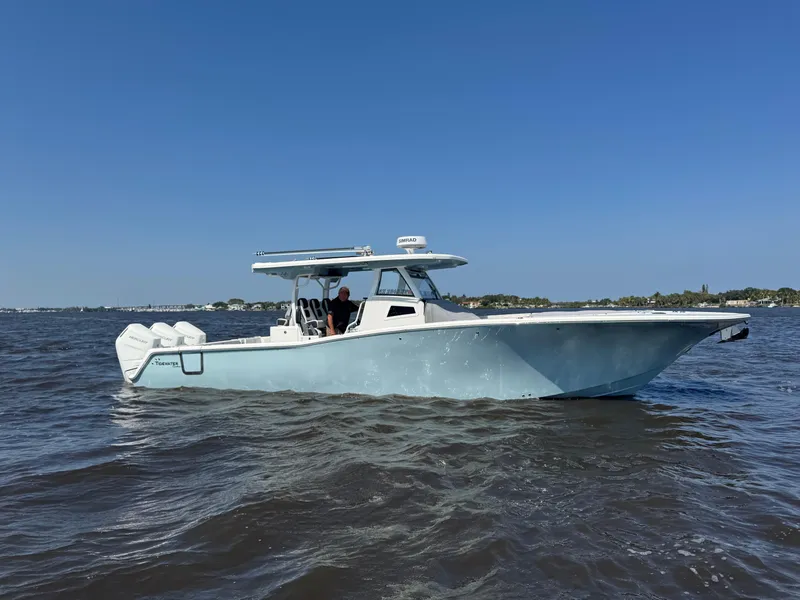 Slide: The Image of 2024 Tidewater 380 CC Adventure boat cruising on open water under clear blue sky. - 46