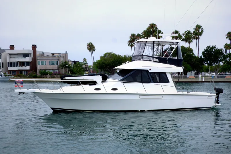 The Image of 2003 Mediterranean 38 Convertible yacht on calm water near waterfront homes. - 0