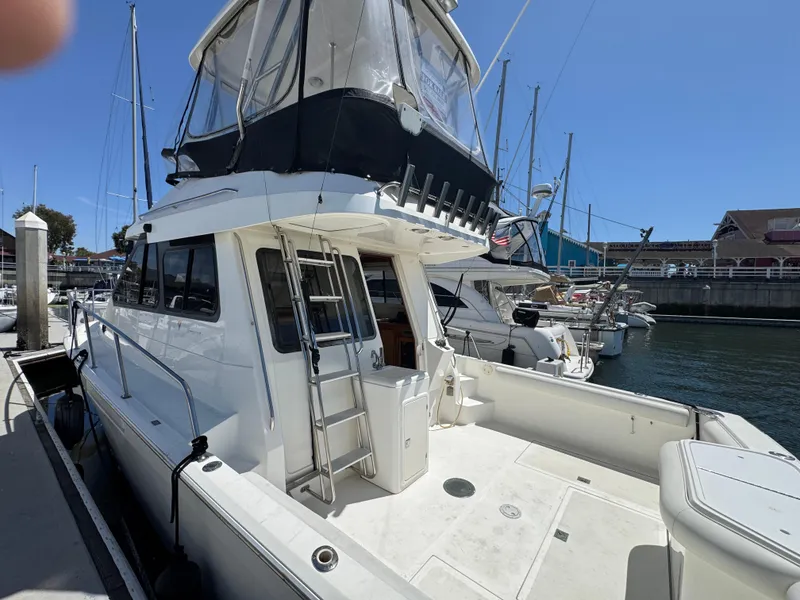 Slide: The Image of 2003 Mediterranean 38 Convertible yacht docked at marina, featuring spacious deck and flybridge. - 10