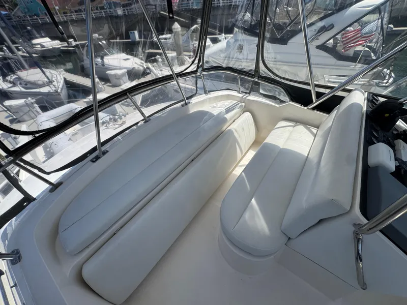 Slide: The Image of 2003 Mediterranean 38 Convertible boat interior with white seating and marina view. - 47