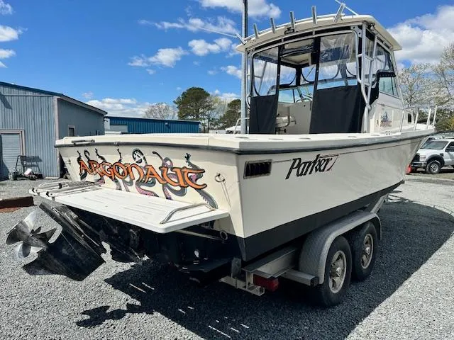 Slide: The Image of 2001 Parker 2510DVWA boat on trailer, featuring "Argonaut" graphics, parked outdoors. - 2
