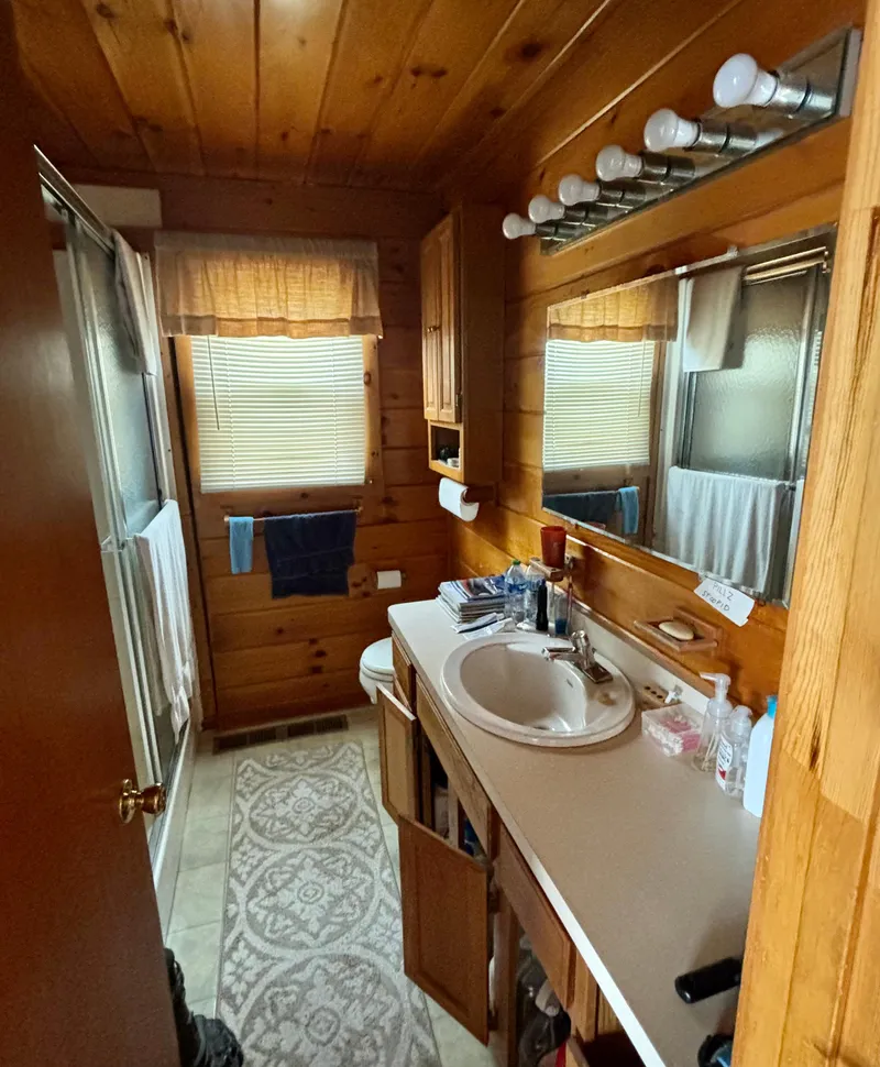 Slide: The Image of Wood-paneled houseboat bathroom with sink, mirror, and natural light, Custom model, 1990. - 14