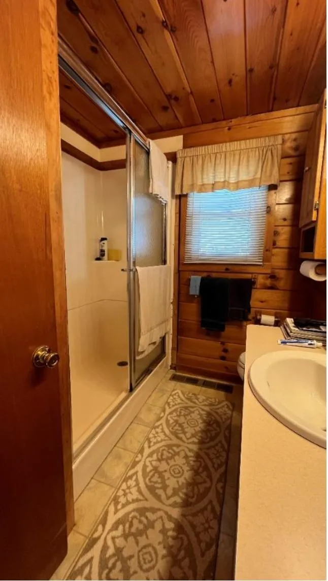 Slide: The Image of Wood-paneled houseboat bathroom with shower, sink, and decorative rug, Custom model, 1990. - 15