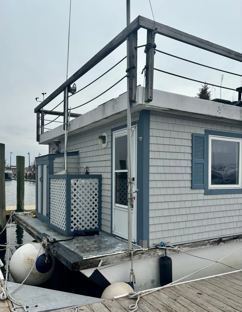 Slide: The Image of Custom 1990 houseboat with blue shutters and rooftop deck, docked at a marina. - 2